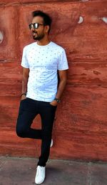 Full length of young man standing against brick wall