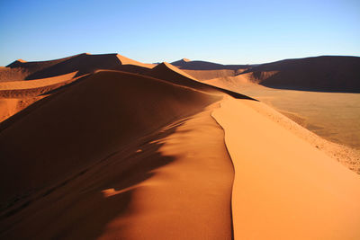 Sand dunes in desert against clear blue sky