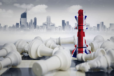 Digital composite image of chess pieces with flag against buildings in city