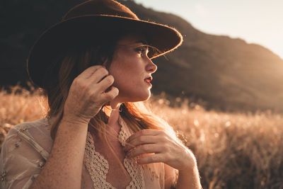 Portrait of woman wearing hat standing on field