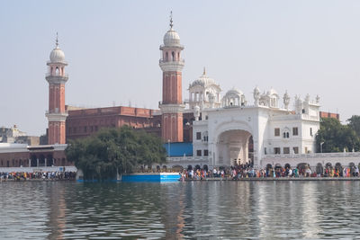 Buildings by river against clear sky