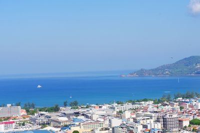 Aerial view of townscape by sea against clear blue sky