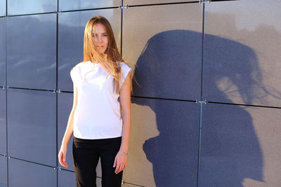 Portrait of young woman standing against window