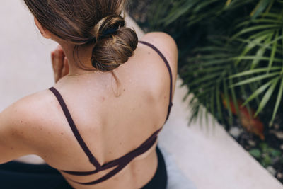 Rear view of woman shoulders during meditation practise with hair in a bun