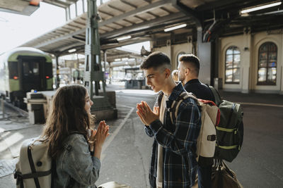 Brother playing leisure game with sister while waiting for train at railroad station