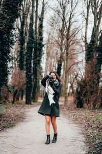 Full length of woman photographing in forest