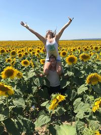Full length of girl standing on yellow flowers against sky