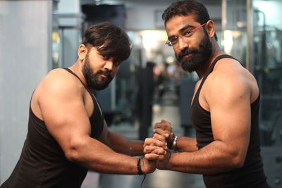 Portrait of muscular men with holding hands standing in gym