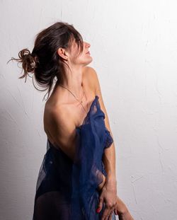 Portrait of young woman standing against wall