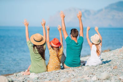 Rear view of people enjoying at beach against sky