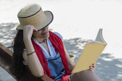 High angle view of woman reading book while sitting on bench