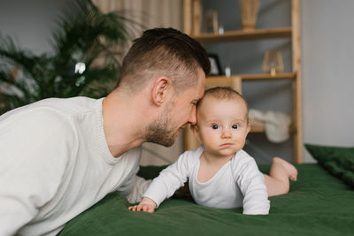 Caucasian father and son in the bedroom on the bed. daddy snuggles up to his baby