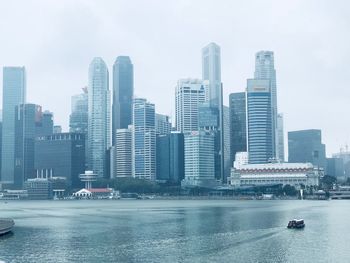 Modern buildings by river against sky in city