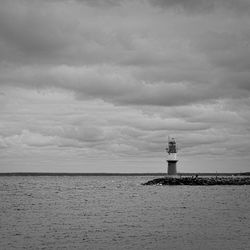 Lighthouse by sea against sky