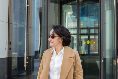 Mid adult woman looking away while standing by window