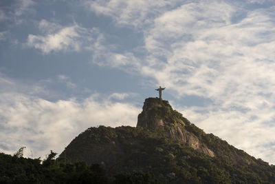 Low angle view of cross on mountain against sky