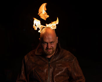 Portrait of man standing against black background