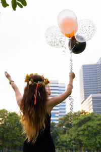 Midsection of woman with balloon balloons against sky