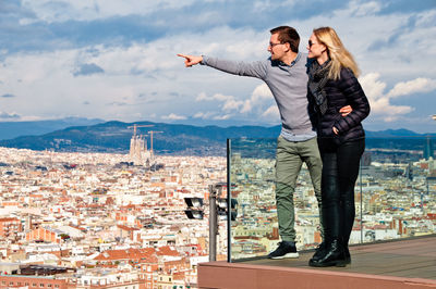 Couple looking at cityscape while standing on balcony