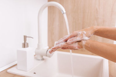 Cropped hand washing hands in sink