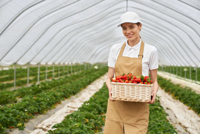 Young woman standing by tree in greenhouse