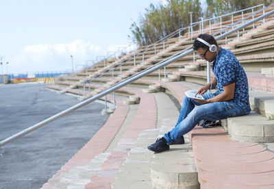 Full length of man using digital tablet sitting on steps