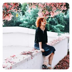 Full length of young woman looking down while standing against plants