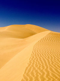 Scenic view of desert against clear blue sky