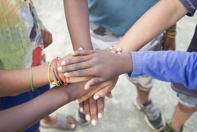 Anonymous group of different race children putting hands together in an outdoor natural environment concept of togetherness