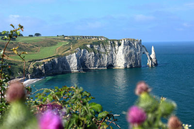 Scenic view of rocks by sea against sky