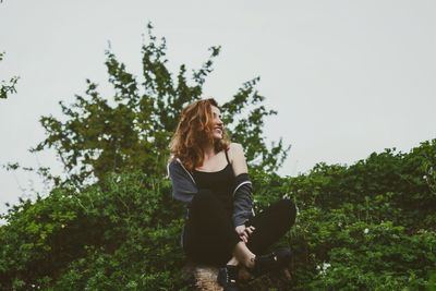 Woman sitting in park against sky