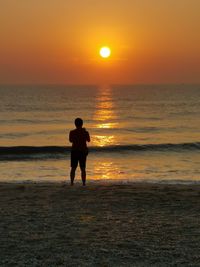 Silhouette man standing on beach against sky during sunset