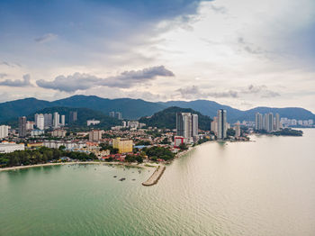 Scenic view of sea by city buildings against sky