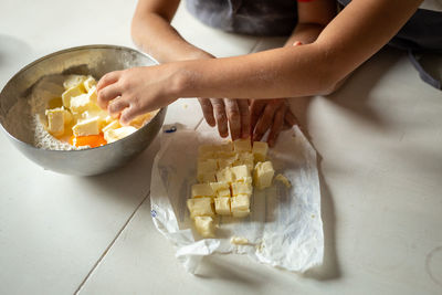 Close view of children hands adding butter to flour