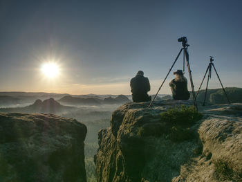 Couple tourists with tripods and cameras take pictures to the background of beautiful hills and sky