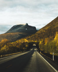 Road passing through landscape against cloudy sky