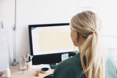 Rear view of female nurse working at computer desk in office