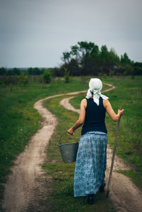 Rear view of woman holding umbrella on field