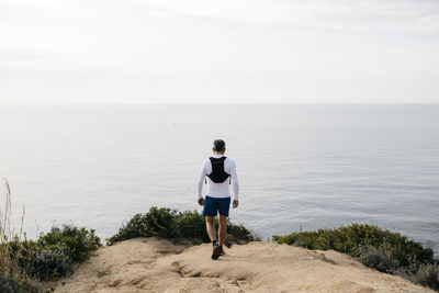 Rear view of man looking at sea against sky