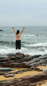 Woman with arms outstretched standing deep in sea water