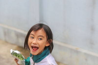 A young little girl is laughing with decayed teeth and a cake bag in a hand