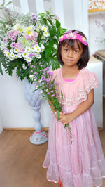 Portrait of cute girl standing by potted plant