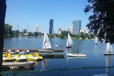 Boats in river by city against clear sky