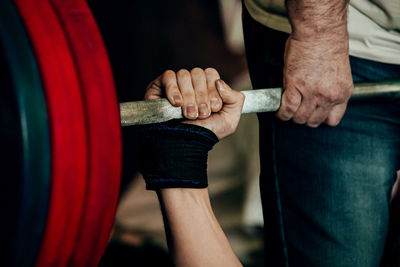 Midsection of man holding dumbbell