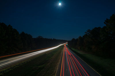 Light trails on road against sky at night