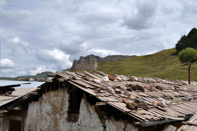 Houses on abandoned building by mountain against sky