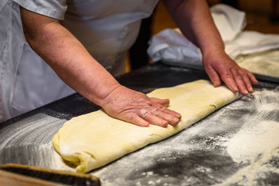 Midsection of man preparing cookies with dough at counter