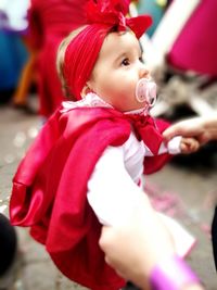 Cropped hand of woman holding baby in city during carnival