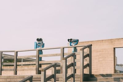 Low angle view of coin-operated binoculars against clear sky