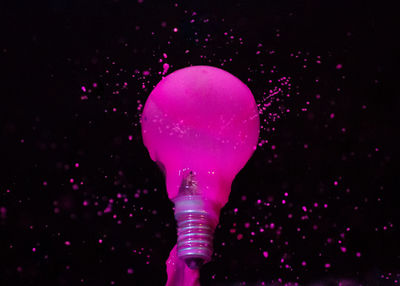 Close-up of electric bulb with pink liquid against black background